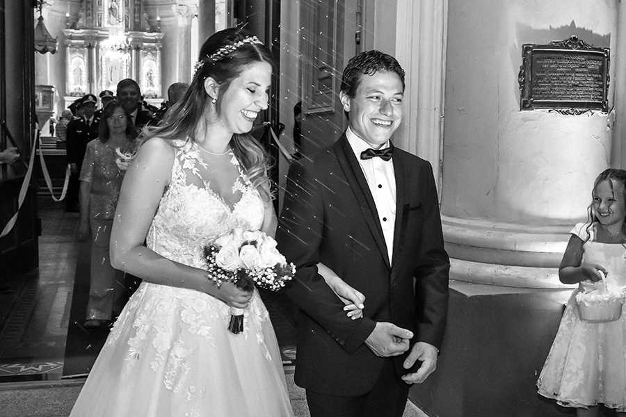 Novios saliendo de la iglesia el día de su boda. Vestido de novia en foto blanco y negro. Barby Massei fotografía. Santa Fe.