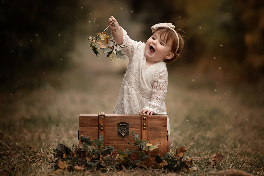 Niña jugando con flores en su book de un año. Sesión fotográfica en San José de la Esquina. Barby Massei