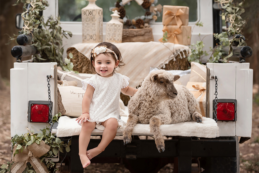 Niña con vestido blanco en la sesión de fotos para Navidad. Corderito en el book de fotos de Santa Fe. Barby Massei