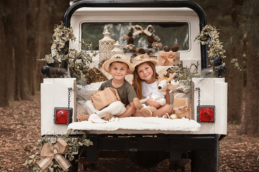 Hermanitos en el campo para las fotos de Navidad. Fiestas felices con el atardecer y decoración navideña. Barby Massei foto.