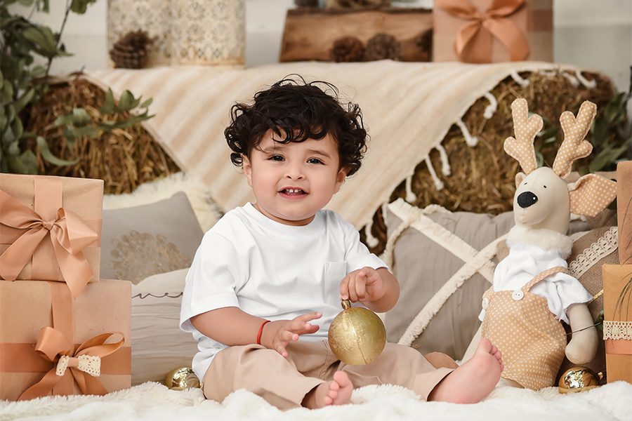 Niña con Reno para la sesión de fotos en la naturaleza. Santa Fe Barby Massei. Bebé con vestido blanco en navidad