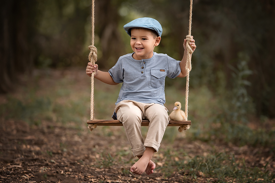 Sesión de familia en el campo. Niño en Hamaca de madera al atardecer para la sesión infantil de Barby Massei.