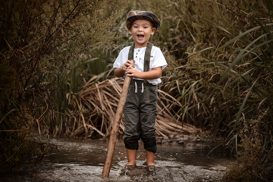 Niño en la laguna para la sesión de fotos en el campo. Boina y jardinero. Book infantil para Barby Massei en Santa Fe.