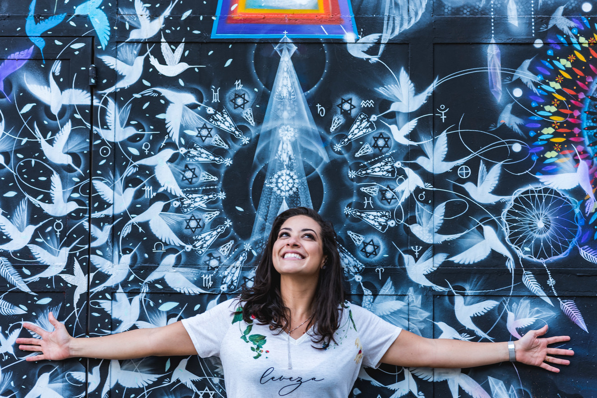 juliana abre os braços acompanhando a pintura da parede