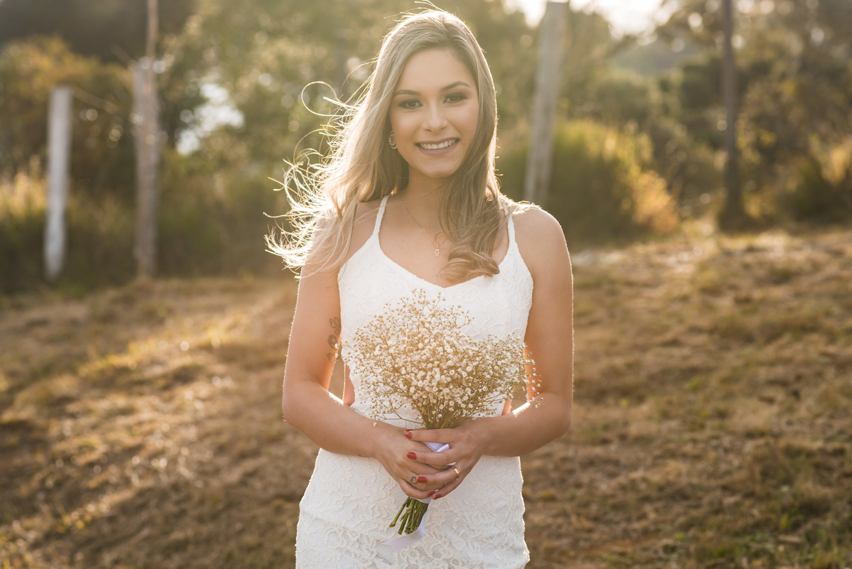 noiva com o buquet na mão ao por do sol