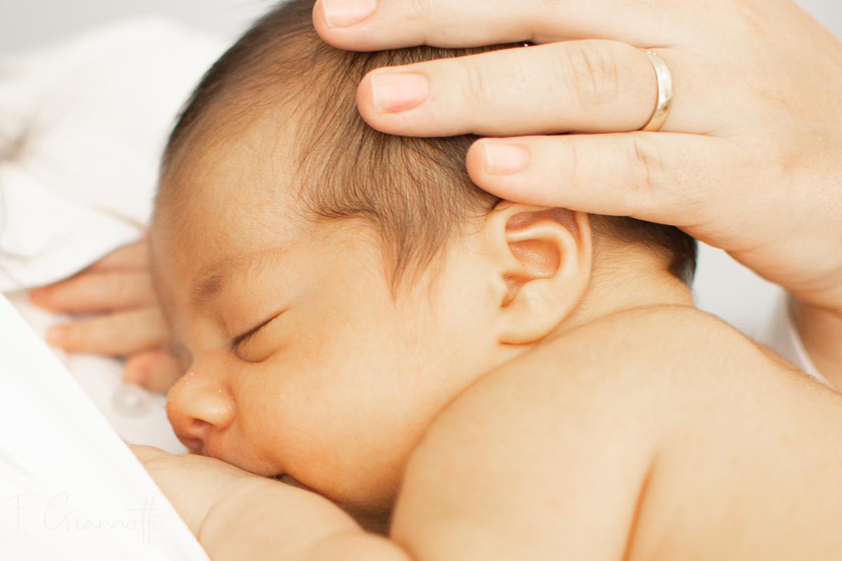 Manos de mamá sobre el bebé en sesión íntima lifestyle