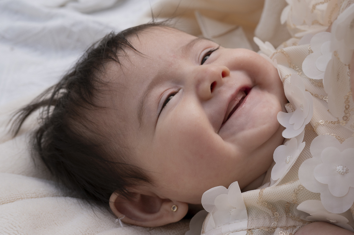 La sonrisa abierta de la bebé ilumina el momento, mostrando cómo el amor se transforma en alegría compartida.