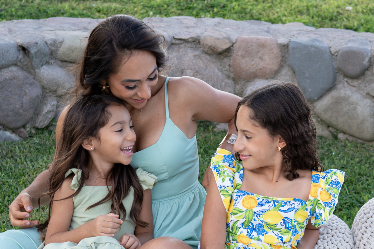 Momentos llenos de cariño entre mamá e hijas durante una sesión fotográfica familiar en exteriores.