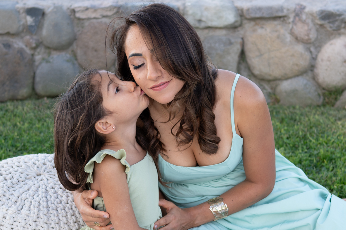 Abrazo entre mamá e hija capturado de manera espontánea durante una sesión fotográfica familiar.