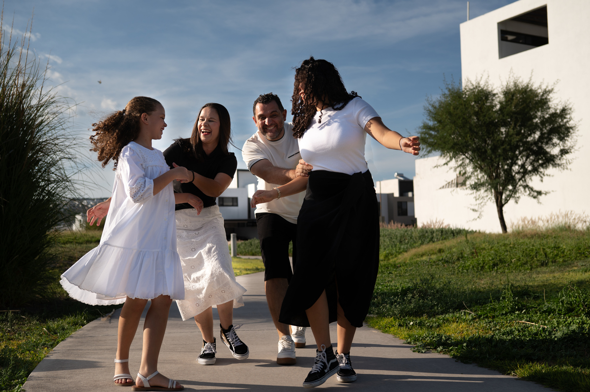 Una familia disfruta de un paseo al aire libre durante una sesión familiar en los jardines de Cañadas del Arroyo, Querétaro. Una fotografía lifestyle llena de movimiento y naturalidad.