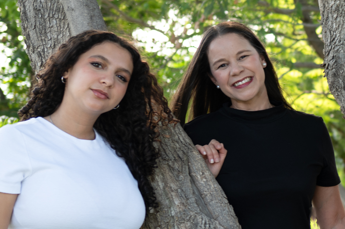 Retrato natural de madre e hija adolescente sonriendo junto a un árbol durante una sesión familiar en Querétaro. Una fotografía espontánea que resalta su complicidad.