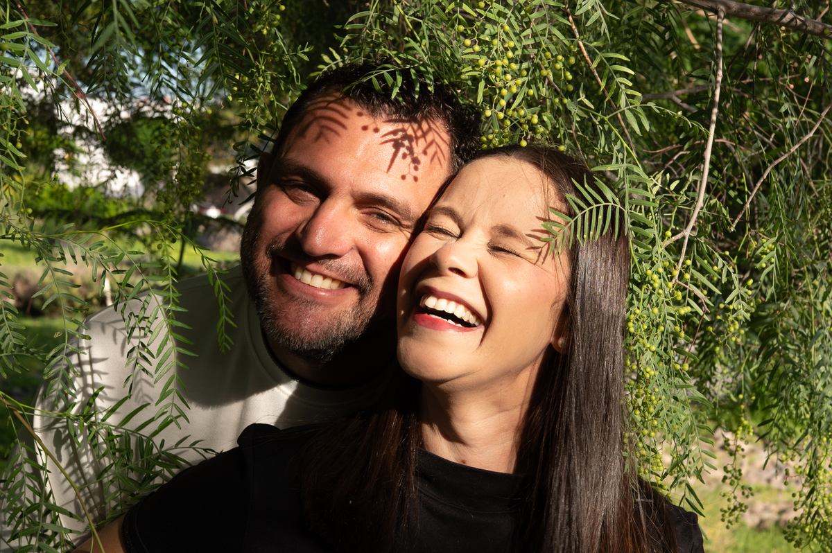 Retrato de pareja sonriendo entre la vegetación durante una sesión familiar lifestyle en Querétaro. La fotografía refleja cercanía y naturalidad.