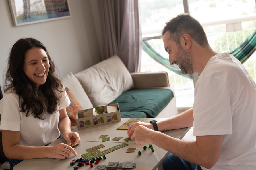 Cami y Lucas jugando un juego de mesa sobre la cama. Sesión de preboda en casa, escenas de su día a día, en Querétaro.