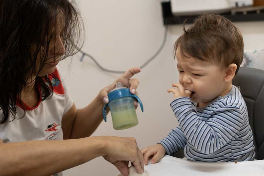 Bebé de un año tirando el agua de su vaso sobre la mesa. Sesión lifestyle de bebé en casa en Querétaro.