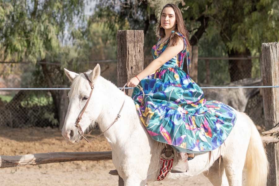 Quinceañera cabalgando un caballo blanco junto al corral, sesión de XV años en Querétaro