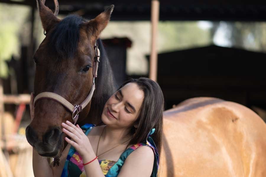 Fotos de XV años en Querétaro: quinceañera sonriendo junto a un caballo café