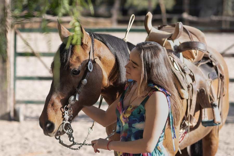Sesión campestre de XV años con la quinceañera junto a un caballo ensillado