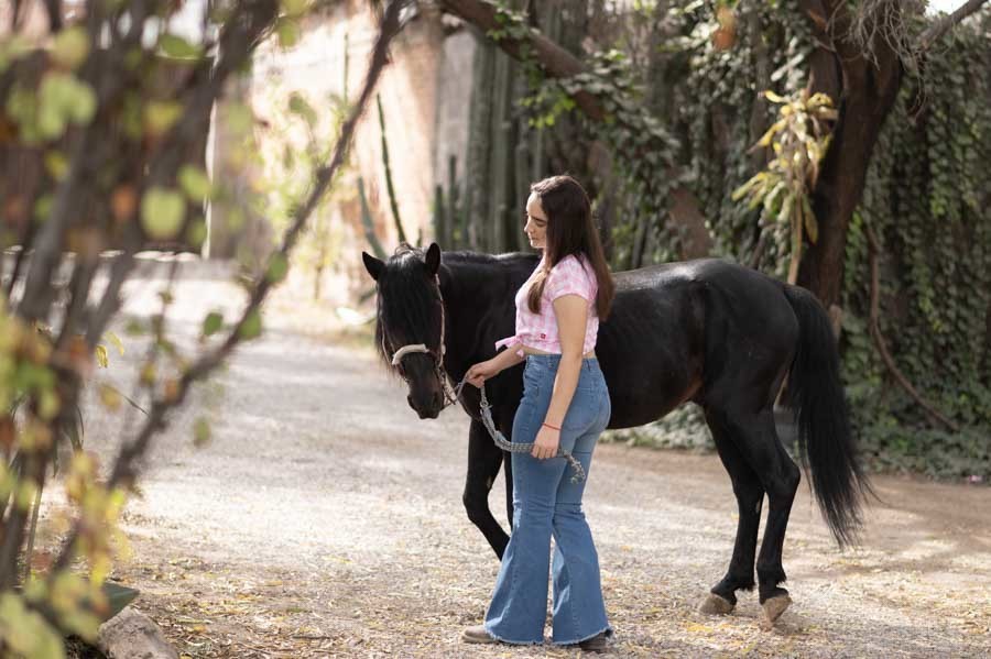 Look casual de XV años: quinceañera en jeans con un caballo negro