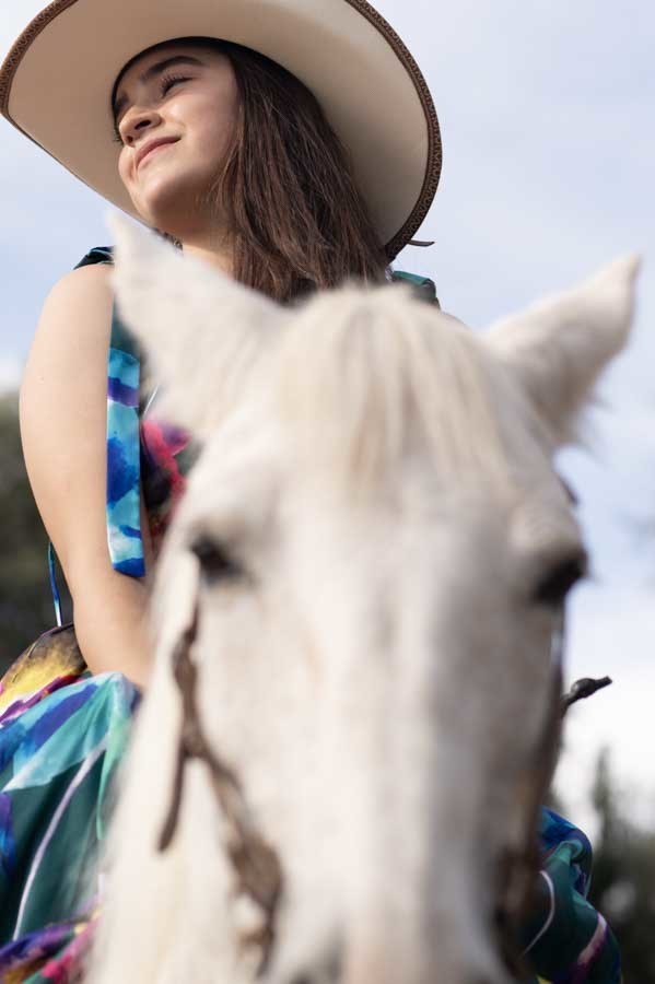 Fotos de quinceañera con sombrero vaquero sobre un caballo blanco con el cielo de fondo