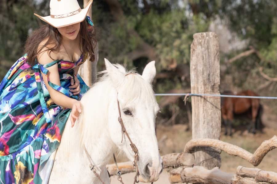 Quinceañera a caballo con vestido floral en una sesión ecuestre de XV años