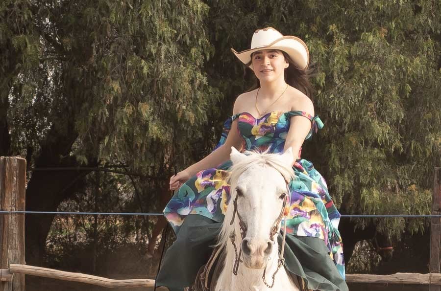 Sesión campestre de XV años: quinceañera cabalgando entre árboles con vestido floral