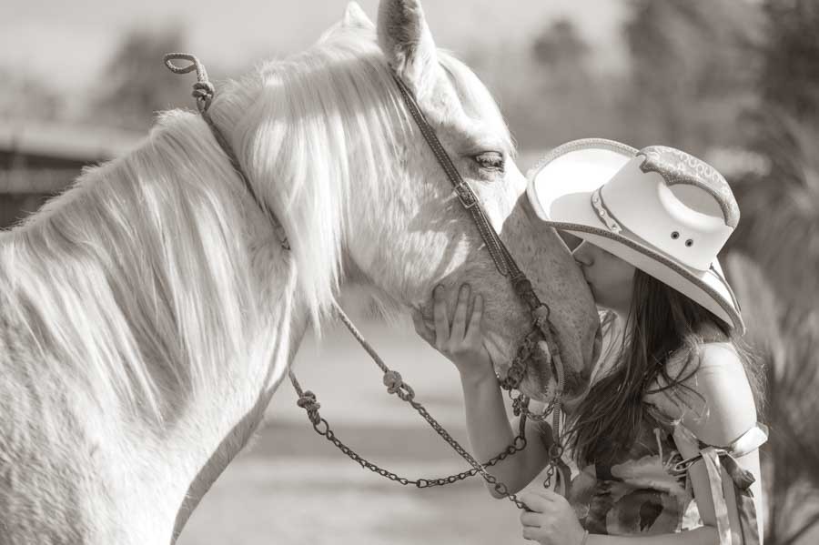 Quinceañera con sombrero dándole un beso a su caballo, foto de XV años en blanco y negro