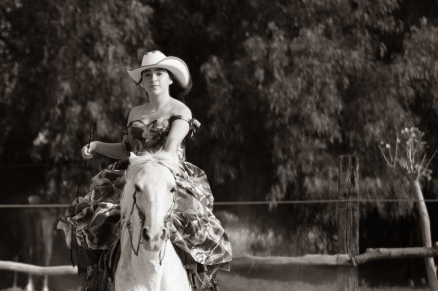 Fotografía de quinceañera en blanco y negro cabalgando un caballo blanco
