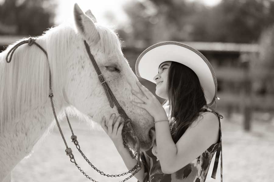 Quinceañera frente a frente con su caballo, retrato ecuestre en blanco y negro