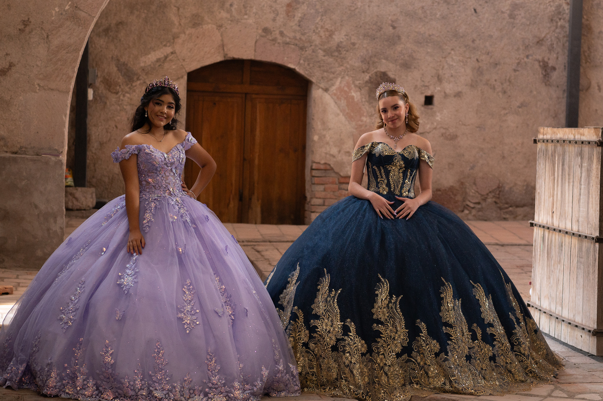 Vestidos de XV años lila y azul marino frente a una puerta antigua de hacienda