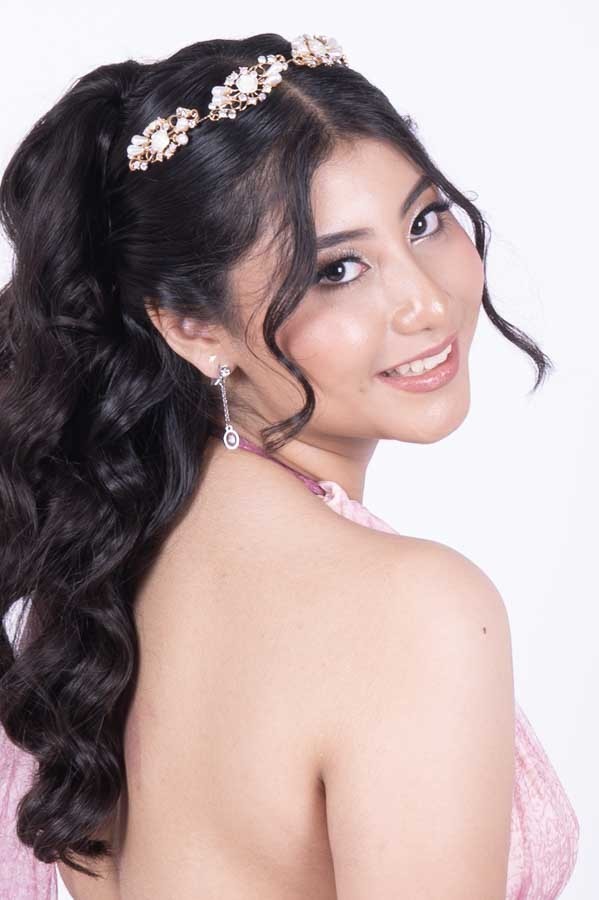 Quinceañera con vestido rosa mirando sobre el hombro, retrato de XV años en estudio