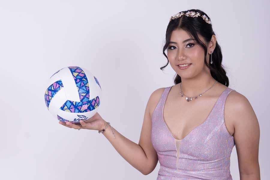Retrato de XV años: quinceañera sonriendo con su balón de voleibol en estudio