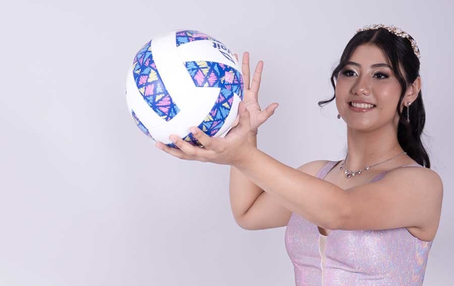Quinceañera con vestido lila sosteniendo un balón de voleibol en su sesión de XV años
