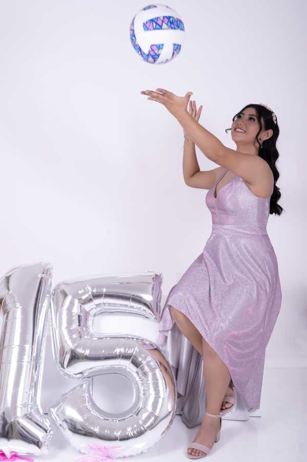 Quinceañera lanzando un balón de voleibol en su sesión de XV años en estudio en Querétaro