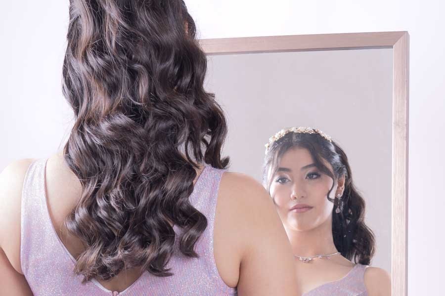 Peinado de XV años con ondas reflejado en un espejo, retrato de quinceañera en estudio