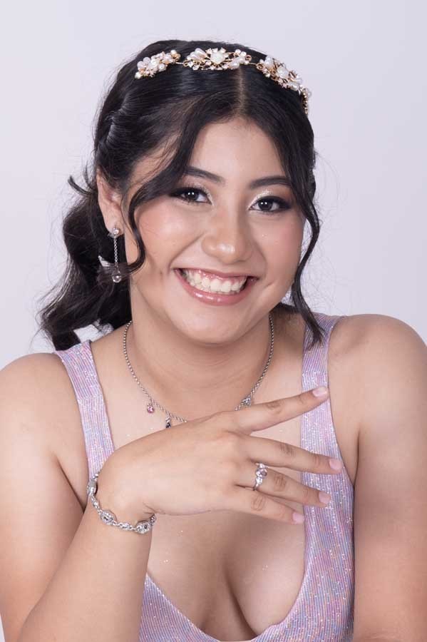 Quinceañera sonriendo con la mano en el pecho, sesión de XV años en estudio en Querétaro