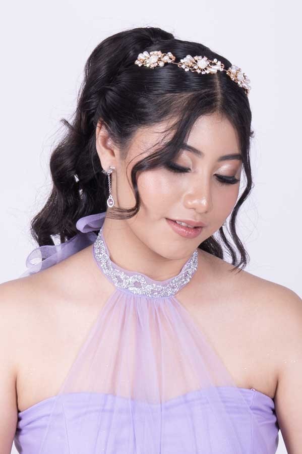 Retrato de quinceañera con vestido lila de cuello halter sobre fondo blanco