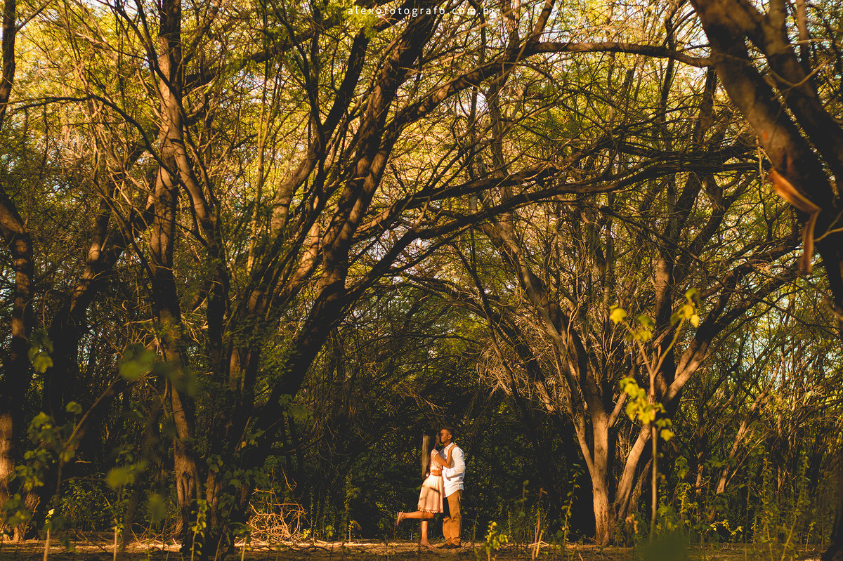 noivos de longe beijando, a noiva levantando o pé durante o beijo