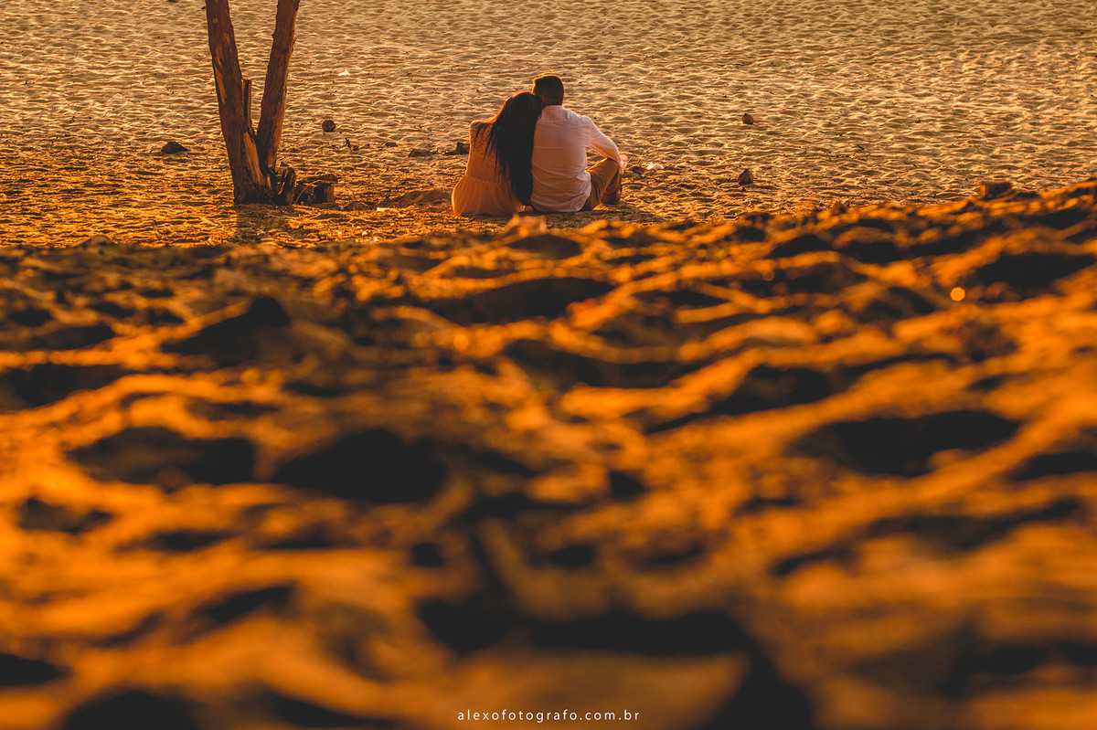 noivos sentados na areia. noiva apoiando a cabeça no ombro do noivo