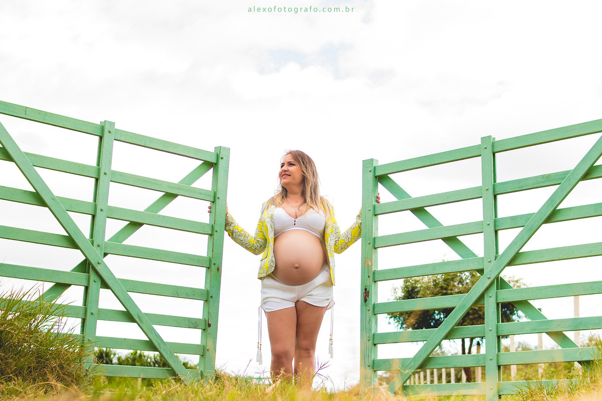 gestante abrindo porteira na paisagem do campo lindo ensaio externo de grávida