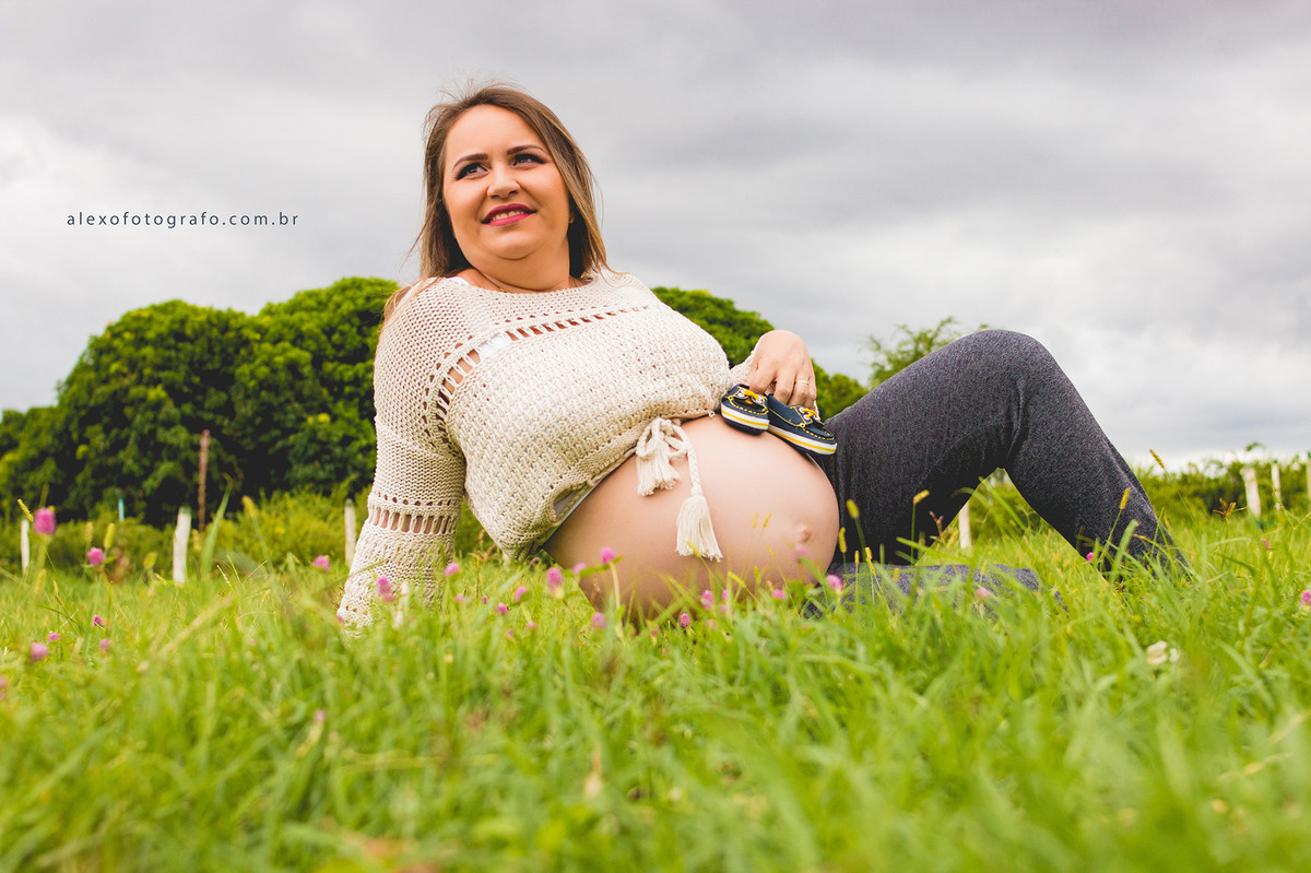 ensaio de gestante sentada na grama com os sapatinhos na barriga