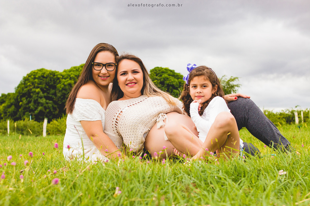 ensaio de gestante sentada na grama com as filhas