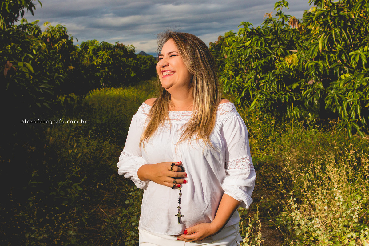 ensaio de gestante vestido branco segurando um terço na barriga