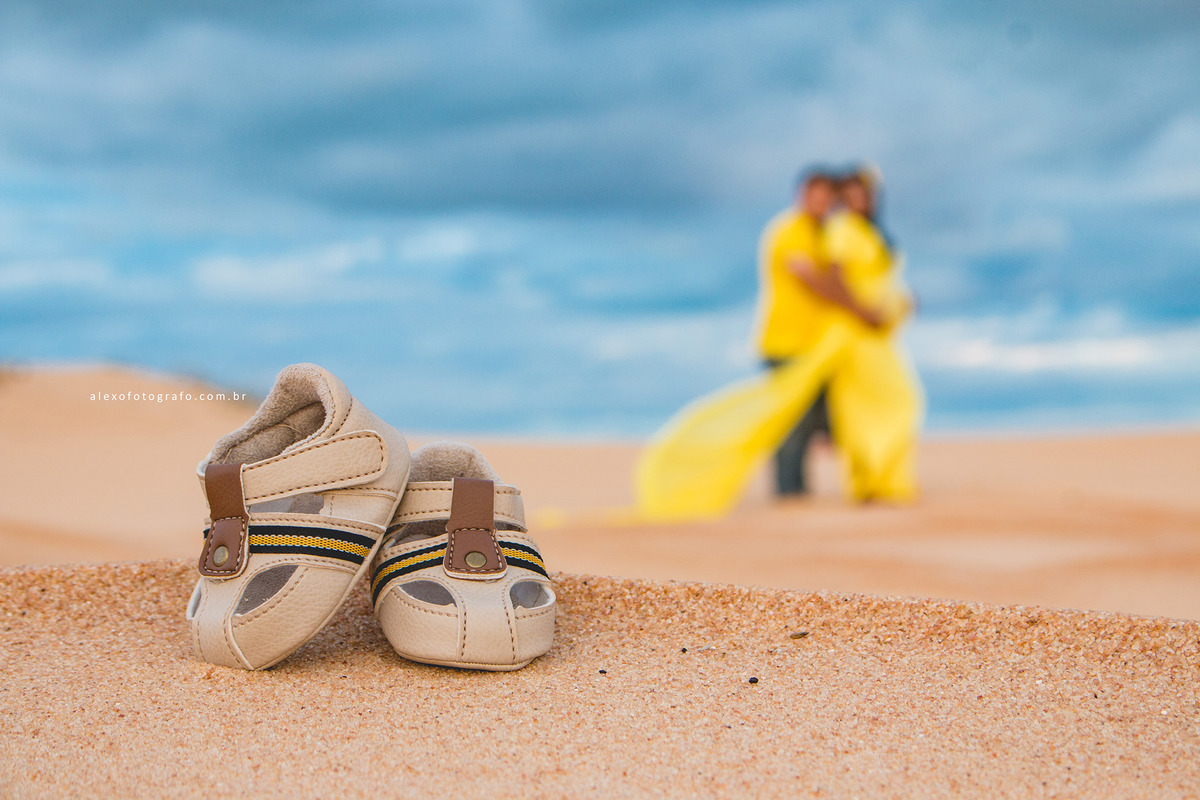 ensaio de gestante, foco nos sapatinhos do bebê na frente e o casal abraçado desfocado no fundo