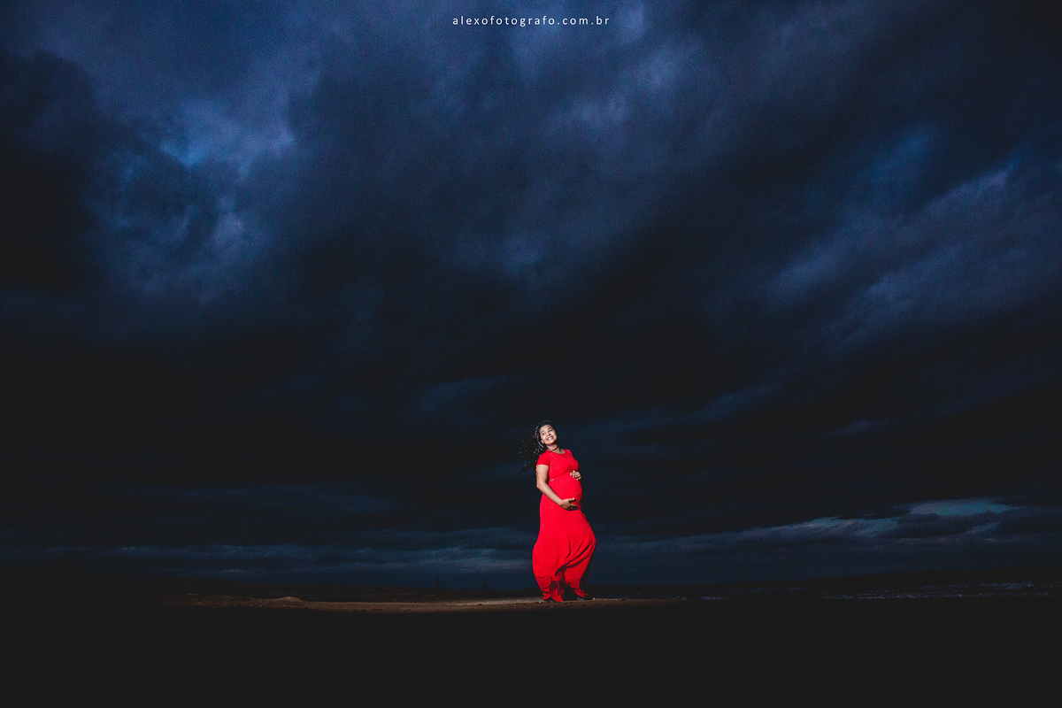 gestante segurando a barriga, vista distante com bastante céu azul de noite