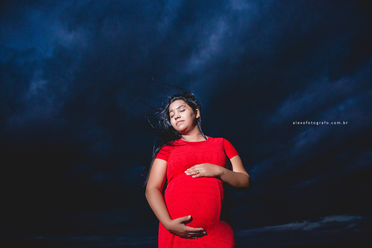 gestante segurando a barriga com bastante céu azul de noite