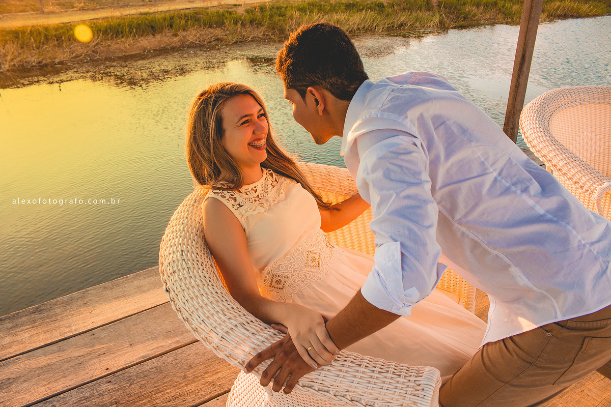 casa, noiva sentada na poltrona e noivo inclinando seu corpo sobre ela como que avançando