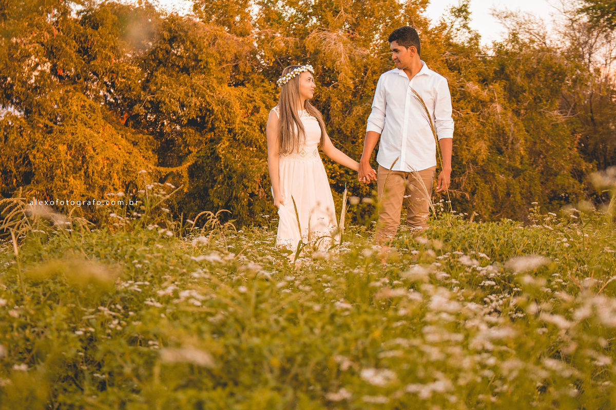 casal caminhando no entre o mato no campo de mãos dadas e se olhando
