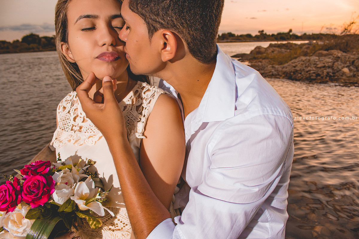 Casal ao por do sol. Noivo tocando o queixo da noiva e dando um xero nos zói