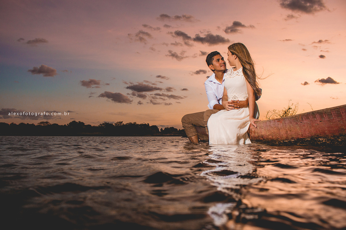 casal sentado no barco ao pôr do sol, os dois trocando olhares