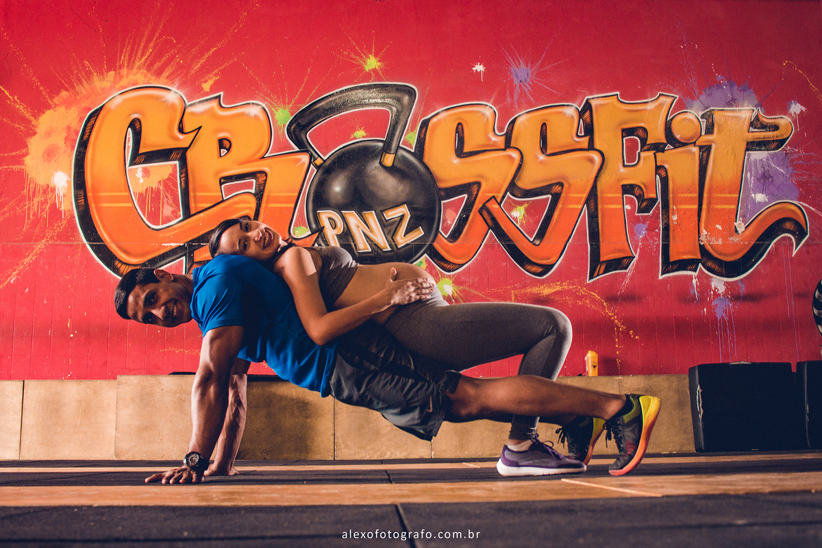 Casal fitness em ensaio de gestante. Lindas fotos de gestante na academia de crossfit. Casal jovem pousando para fotos de gestante por Alex Oliveira